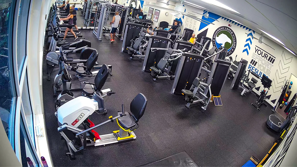 Actual wide-angle photograph of the fitness room with treadmills, bikes and strength machines
