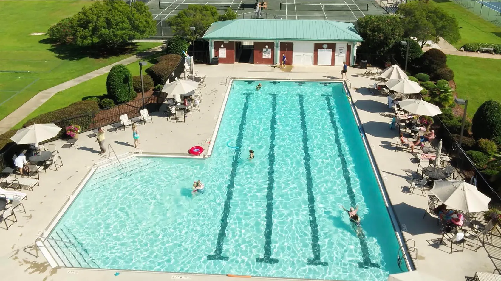 Actual aerial photograph of the outdoor lap pool with lane lines, umbrellas and the cabana